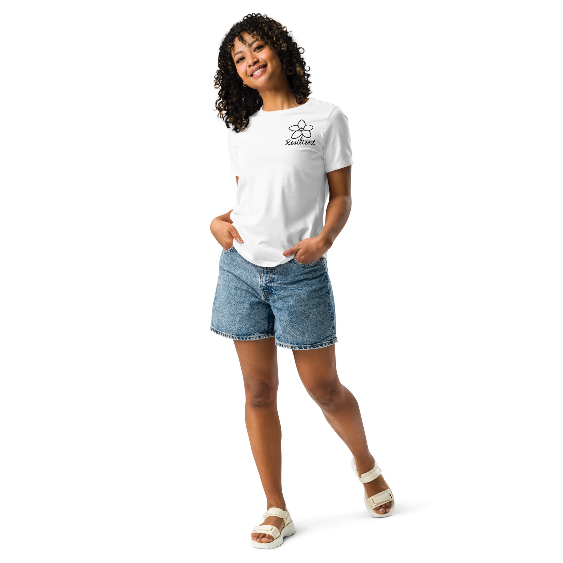 Full view of woman wearing white short-sleeve EverHardy t-shirt, standing with hands in pockets.